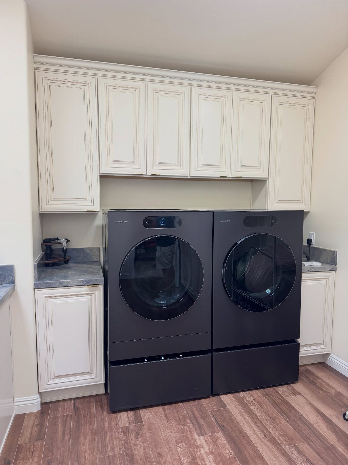Dark grey washer and dryer set elevated on matching laundry pedestals in a room.