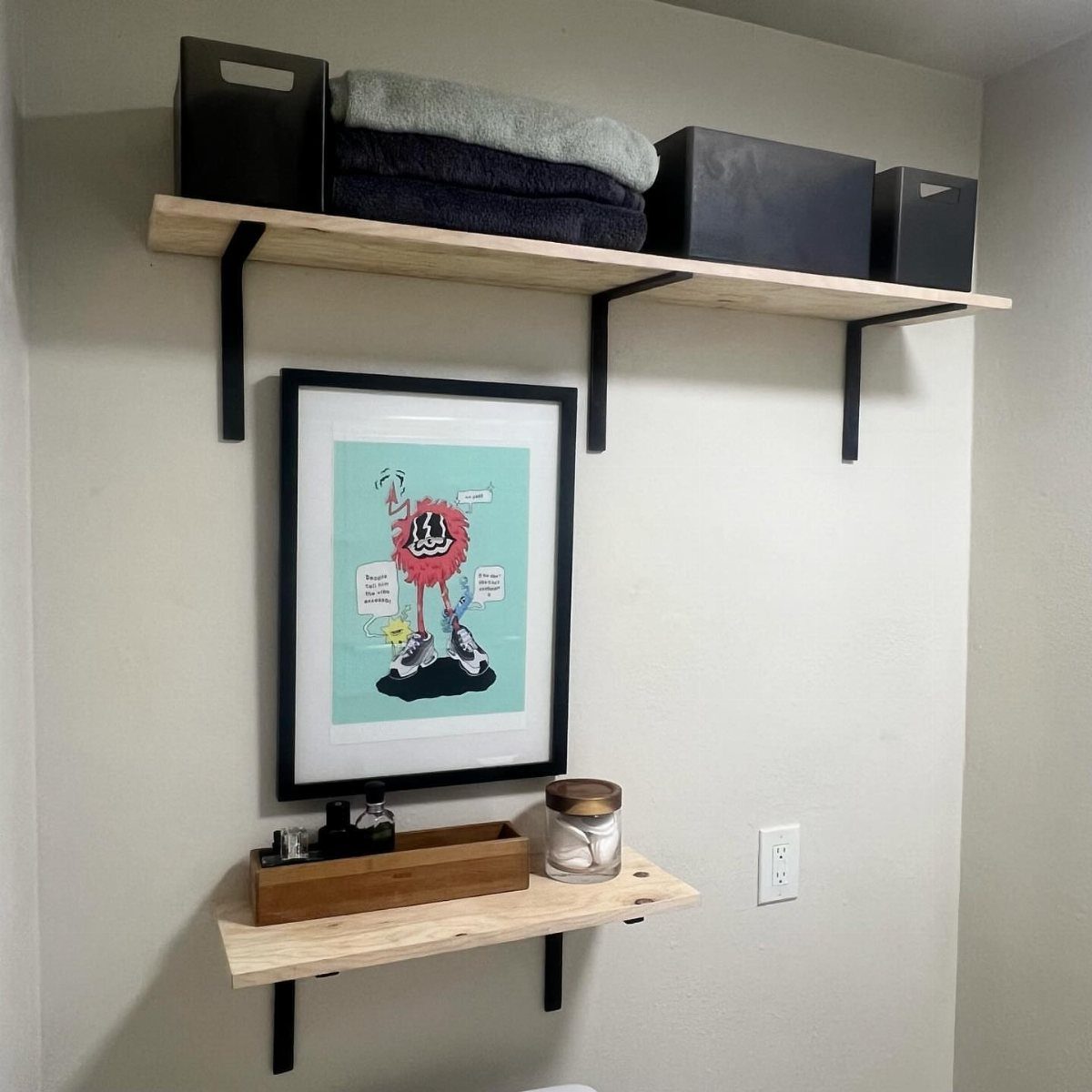 Wooden shelves supported by black metal brackets on a grey wall with decor.